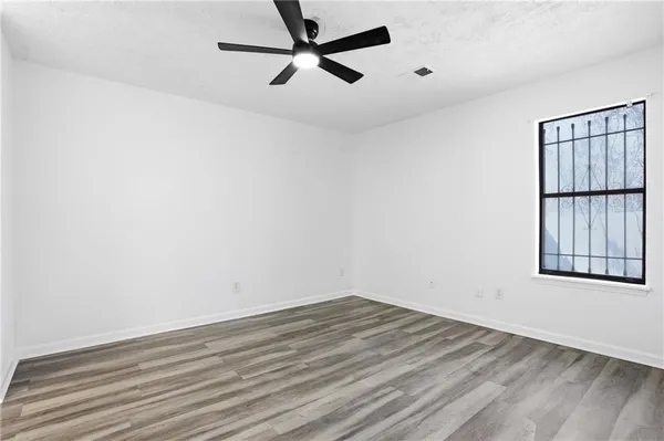 an empty room with wooden floor and windows