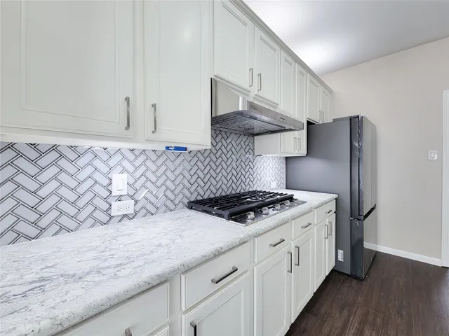 a view of an empty room with wooden floor fireplace and a window