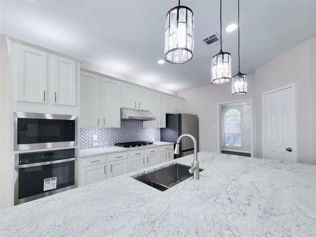a view of an empty room with wooden floor and a ceiling fan