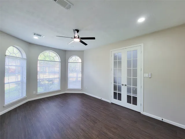a view of empty room with wooden floor and fan