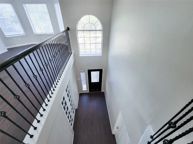 an empty room with wooden floor fan and windows