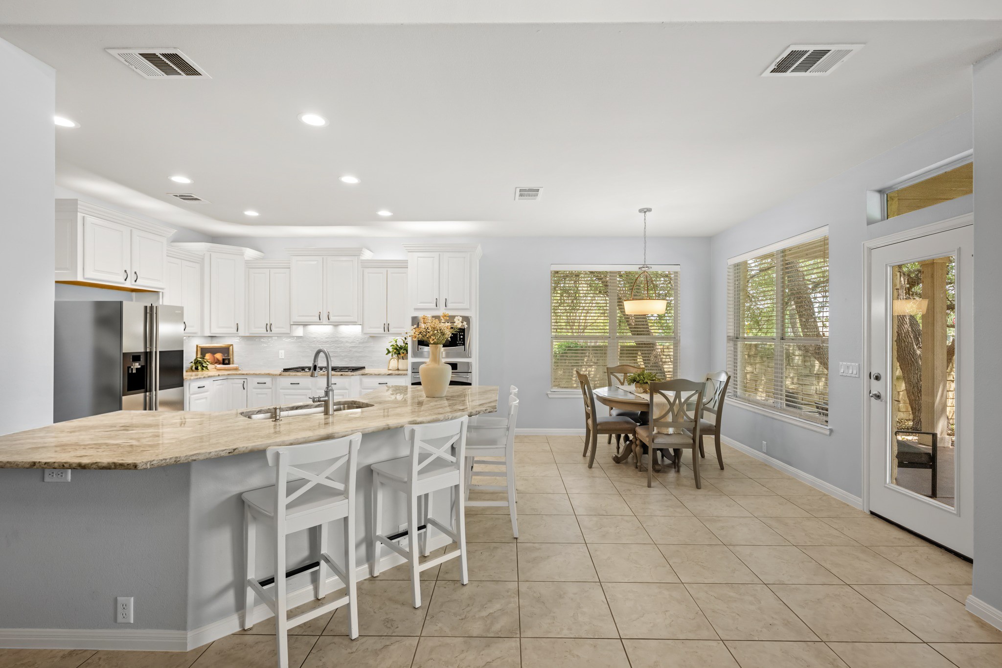 1023 Grassy Field Road Austin, TX 78737 - Photo 11 of 40 Open concept kitchen with white cabinetry, stainless steel appliances, and a central island featuring dolomitic marble countertops.