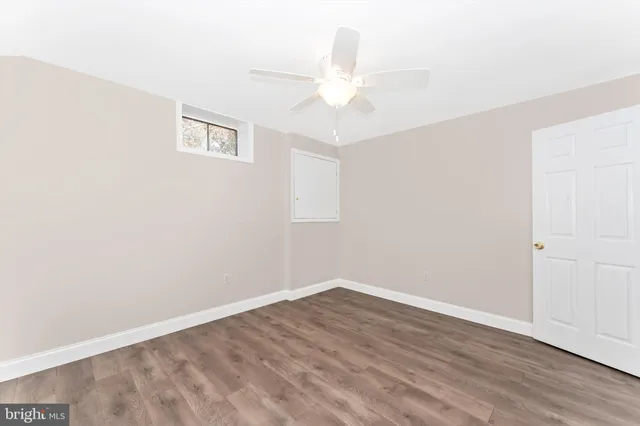 an empty room with wooden floor and fan