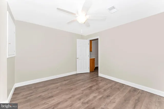 an empty room with a ceiling fan and wooden floor