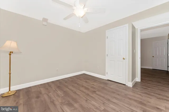 an empty room with wooden floor and fan