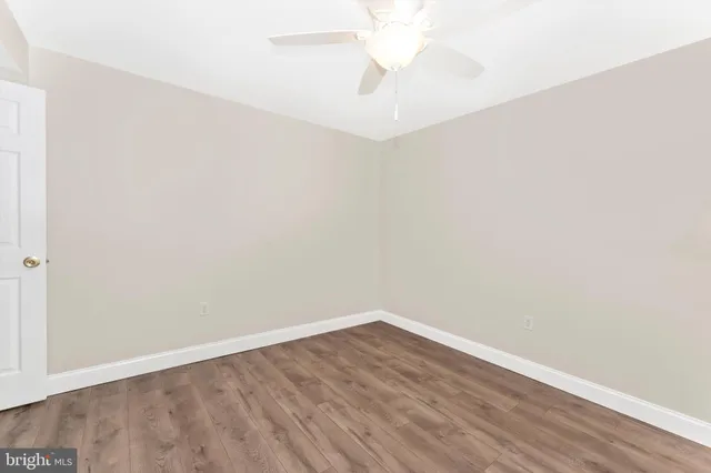 an empty room with wooden floor and fan