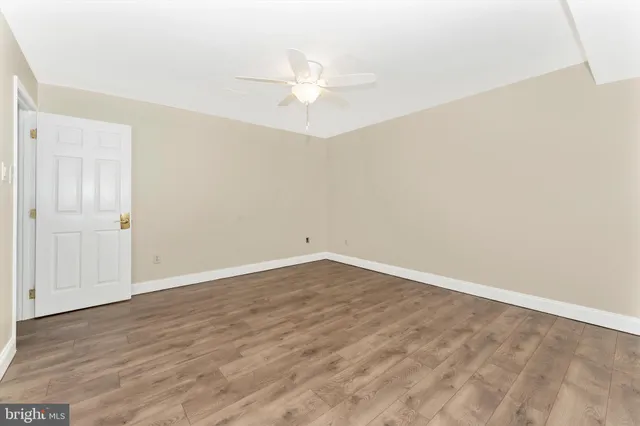 an empty room with wooden floor and fan