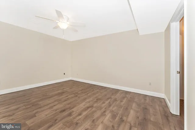 an empty room with wooden floor and fan