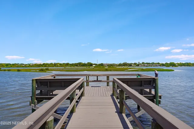 a living room with couches and kitchen view with wooden floor