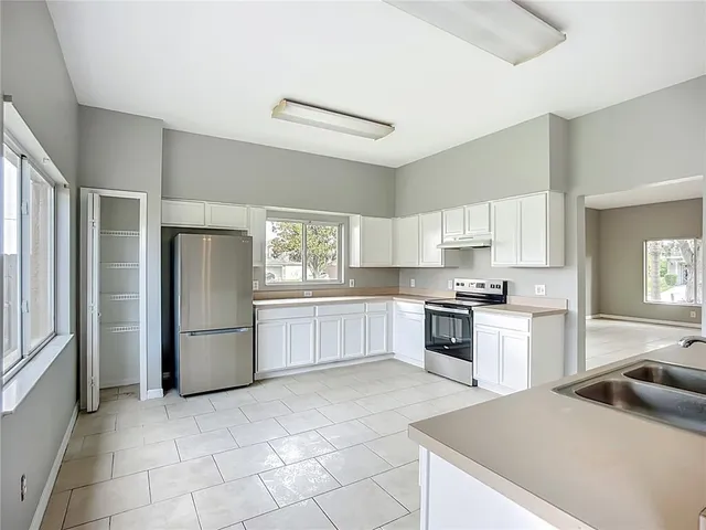 a kitchen with a stove a refrigerator and white cabinets