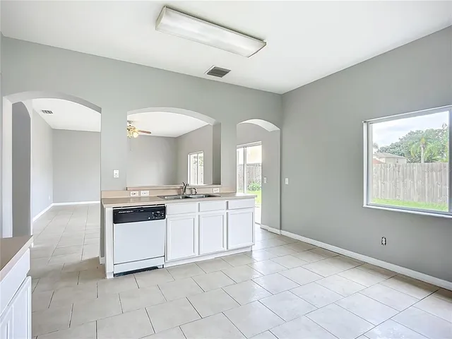 a large white kitchen with a stove a sink a refrigerator and cabinets