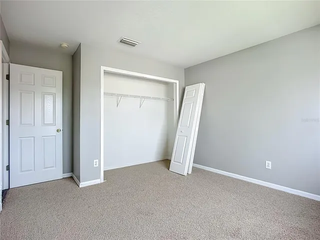 an empty room with a chandelier fan and windows