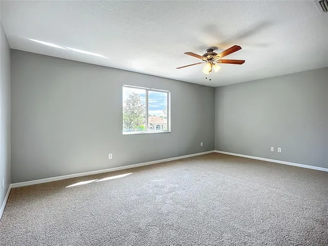 an empty room with windows and fan chandelier
