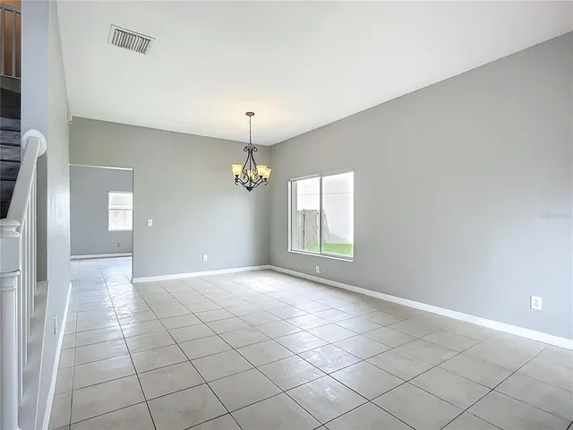 an empty room with windows and chandelier fan