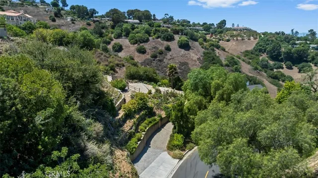 an aerial view of residential house with outdoor space and trees all around