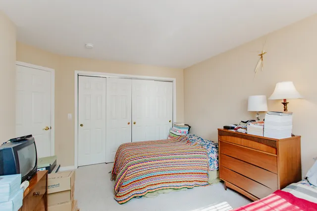 a bedroom with a bed and a lamp on the dresser