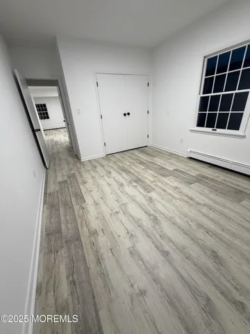 a view of an empty room with wooden floor and stairs