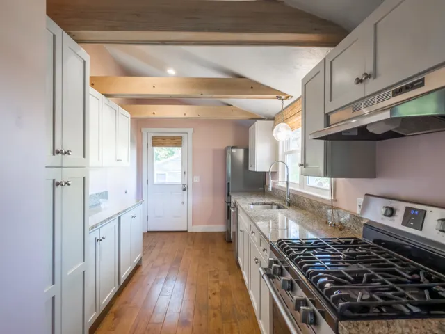 a kitchen with stainless steel appliances granite countertop a stove and a wooden floors