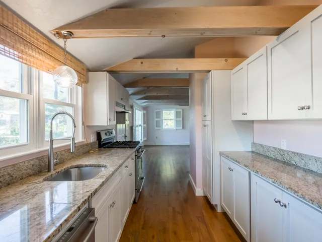 a kitchen with granite countertop a sink stove and cabinets