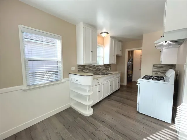 a kitchen with stainless steel appliances kitchen island wooden floors cabinets and a window