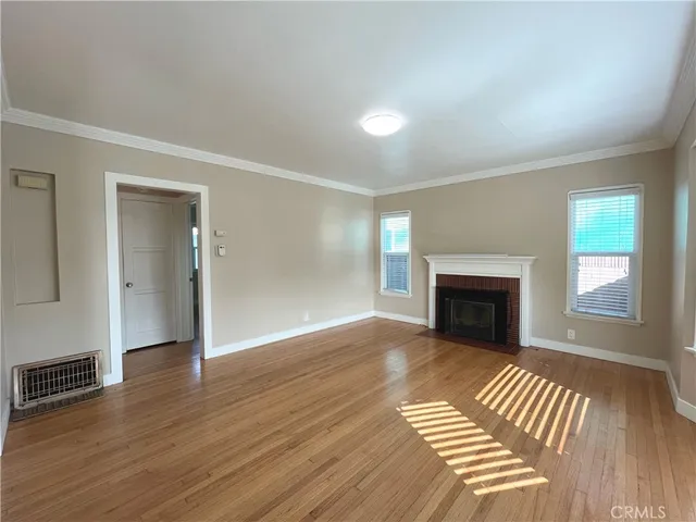 an empty room with wooden floor fireplace and windows