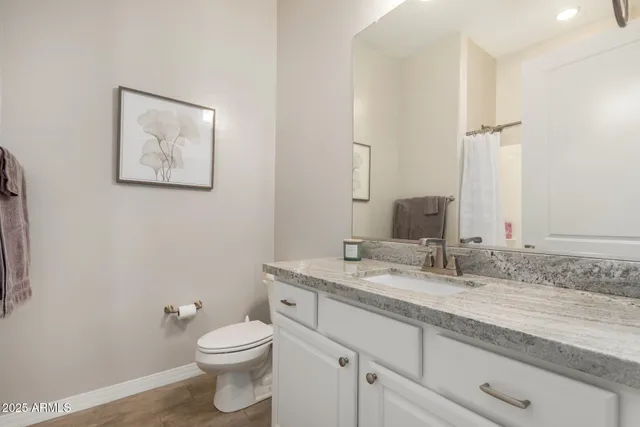 a bathroom with a granite countertop toilet sink and mirror