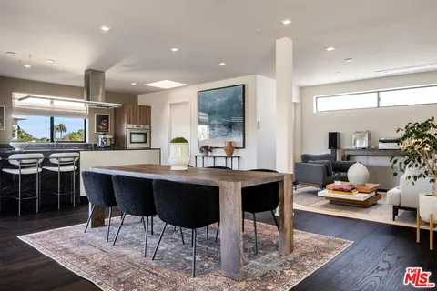 a kitchen with a dining table wooden floor and a view of living room