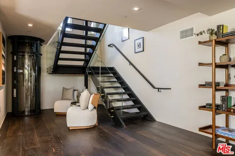 a living room with couches and stairs with wooden floor