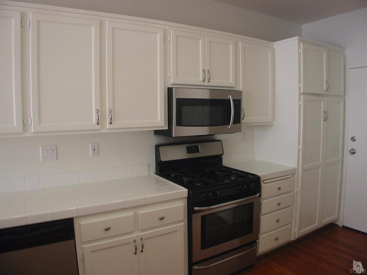 4243 Rusticview Court Moorpark, CA 93021 - Photo 4 of 16 a kitchen with white cabinets and stainless steel appliances