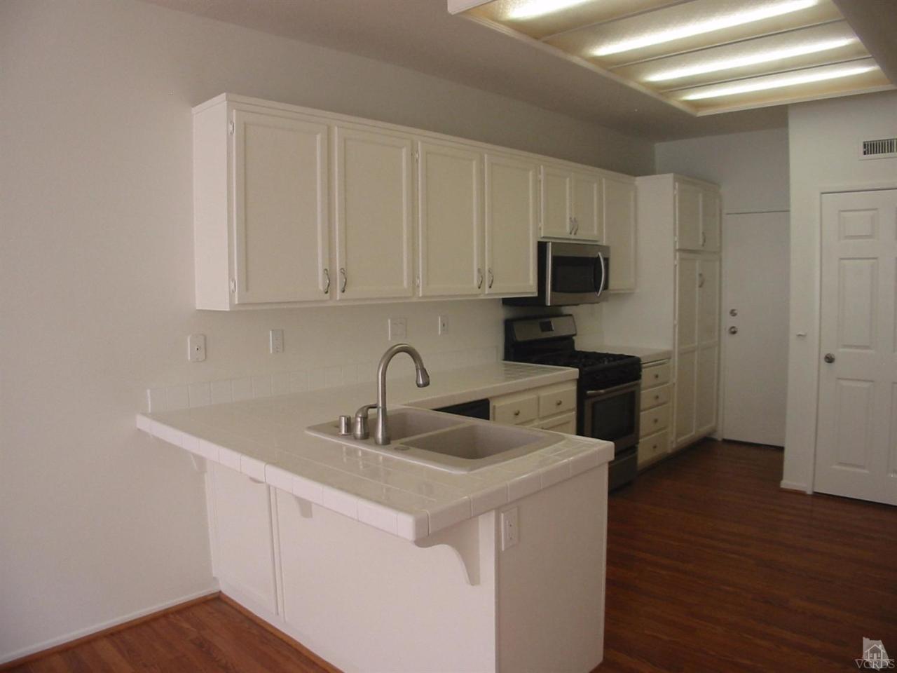 4243 Rusticview Court Moorpark, CA 93021 - Photo 6 of 16 a kitchen with sink a microwave a refrigerator and cabinets