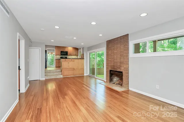 a view of a living room with a fireplace and wooden floor