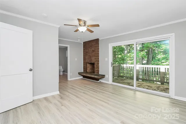 a view of an empty room with wooden floor fireplace and a window