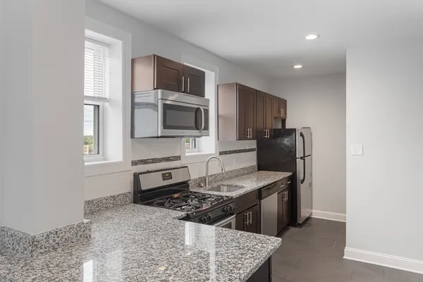 a kitchen with stainless steel appliances granite countertop a stove microwave sink and refrigerator