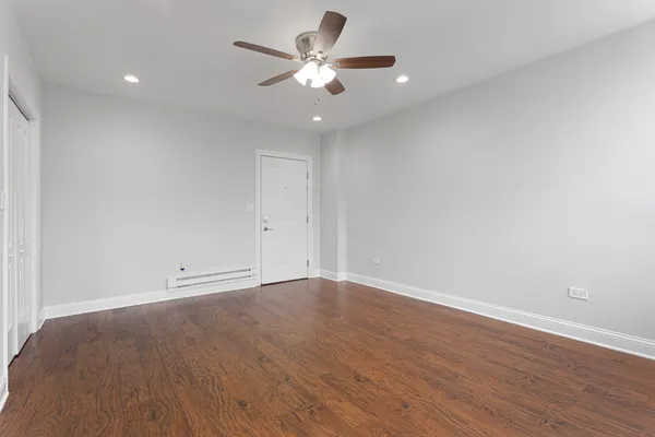 an empty room with wooden floor and a ceiling fan