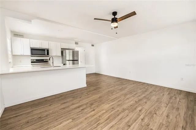 a kitchen with stainless steel appliances a sink cabinets and wooden floor