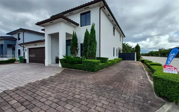 a view of a white house next to a yard and a large tree
