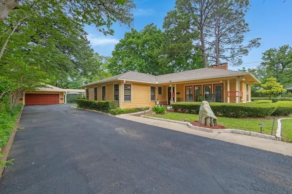 a view of house with a yard and large trees