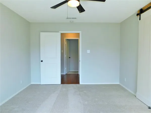 an empty room with hallway closet and chandelier fan