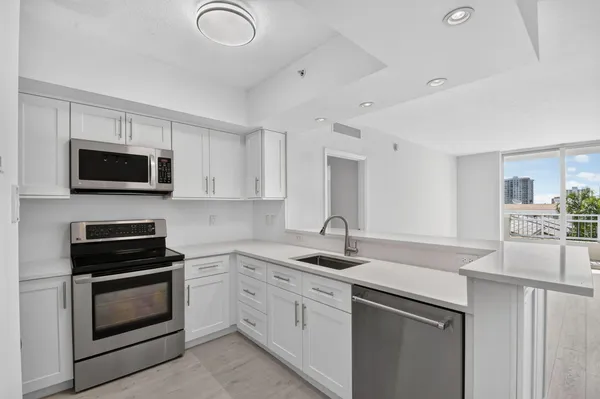 a kitchen with appliances a sink and cabinets