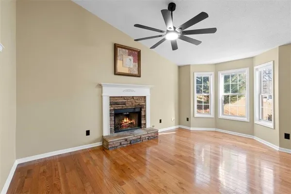 wooden floor in an empty room with a window and a kitchen