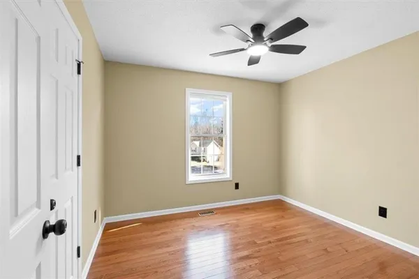a view of an empty room with a window and wooden floor