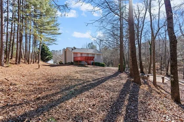 a view of a small house with yard and trees in the background