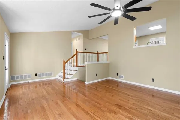 a view of a livingroom with a fireplace a ceiling fan and windows