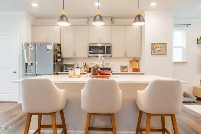 a kitchen with sink refrigerator dining table and chairs
