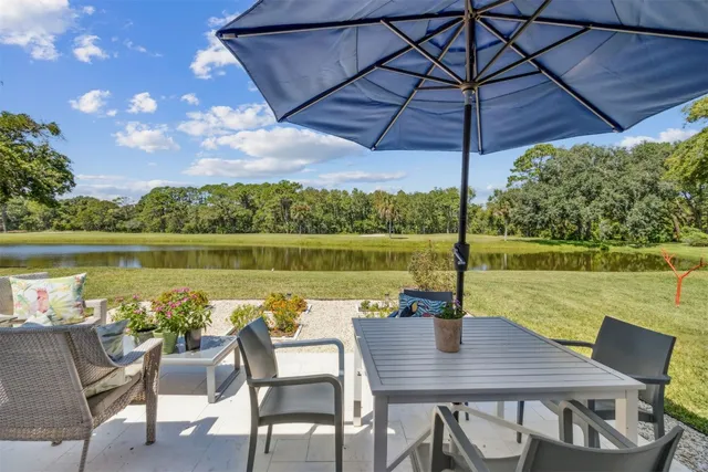 a view of a lake with a table and chairs under an umbrella