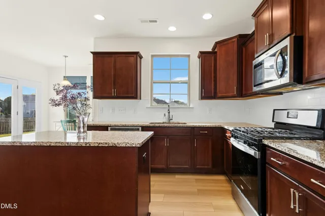 a kitchen with stainless steel appliances granite countertop a sink stove and cabinets
