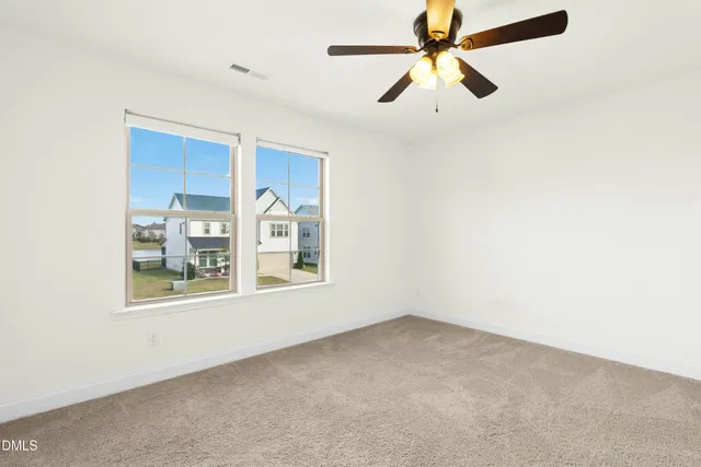 an empty room with windows and fan