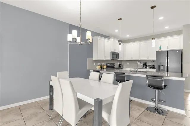 a kitchen with stainless steel appliances kitchen island granite countertop a dining table chairs and a refrigerator