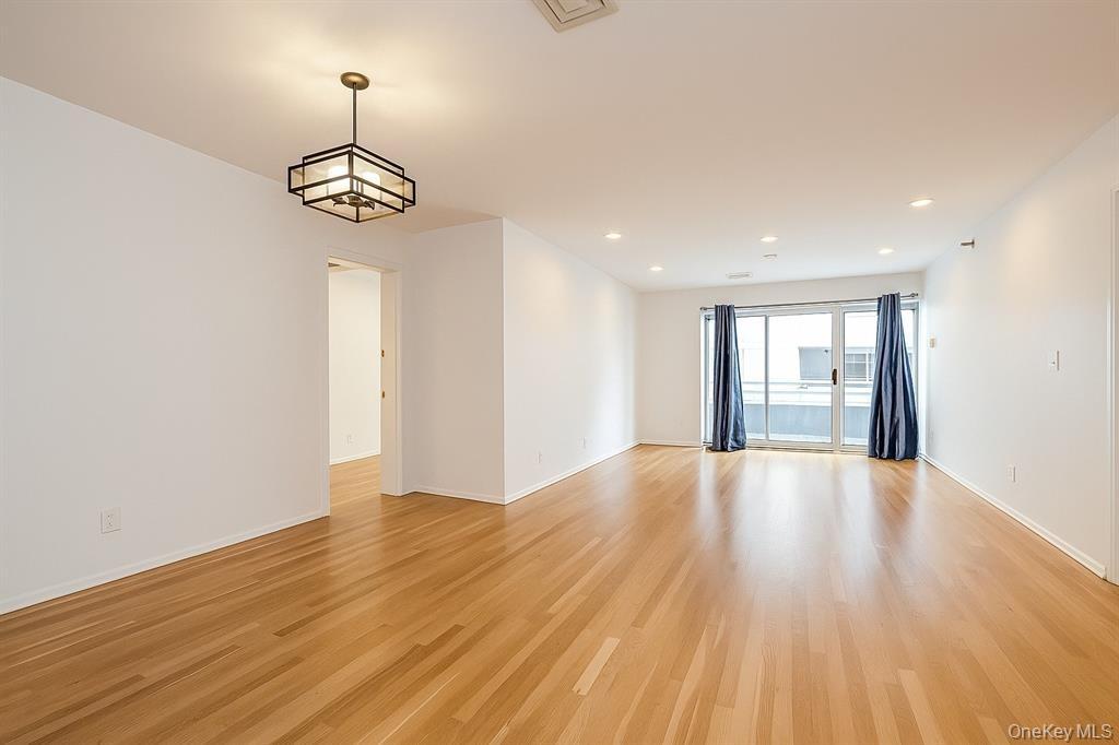 100 Cutter Mill Road, Unit 3E Great Neck, NY 11021 - Photo 5 of 14 a view of an empty room with wooden floor and chandelier