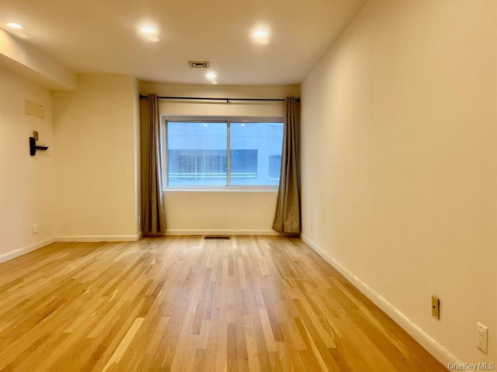 100 Cutter Mill Road, Unit 3E Great Neck, NY 11021 - Photo 10 of 14 a view of an empty room with wooden floor and a window